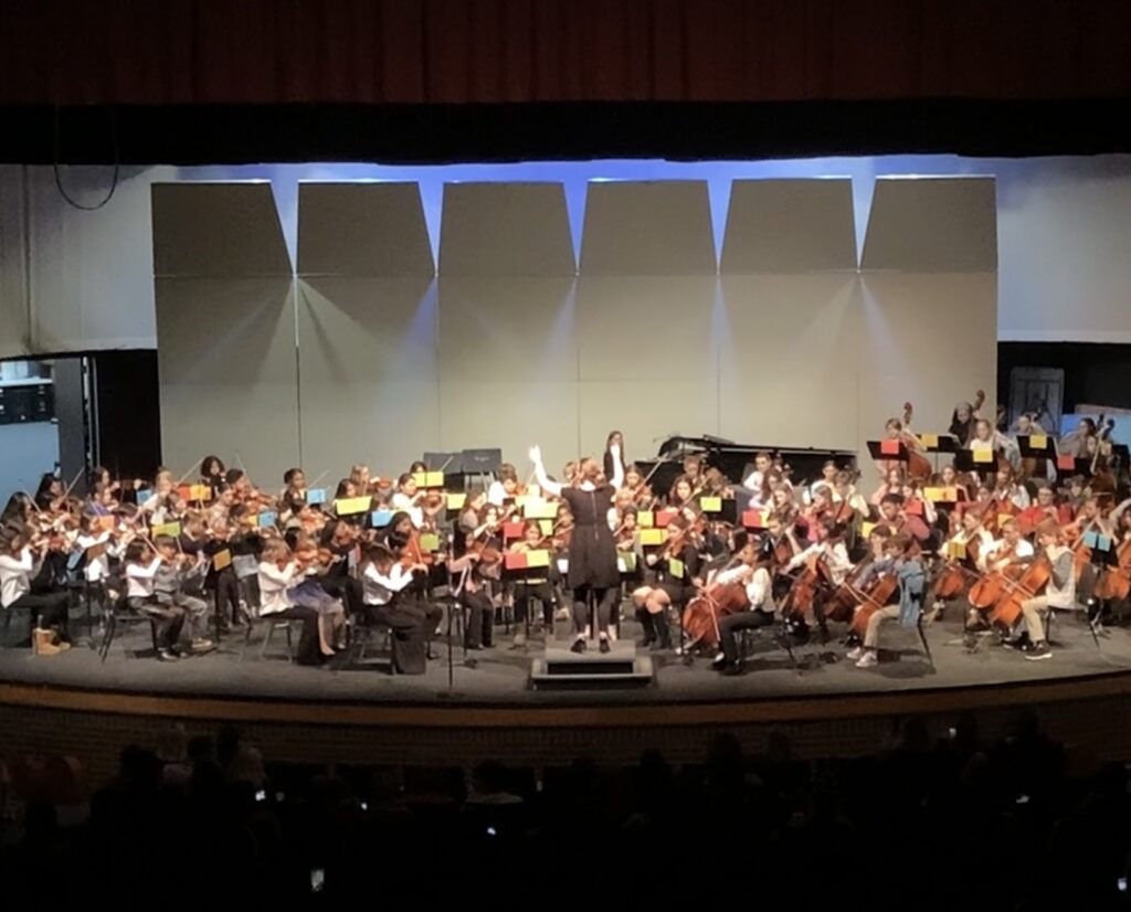 Picture of Tharp orchestra with Ms. Bartholic conducting on the Davidson stage at their November concert 2023.