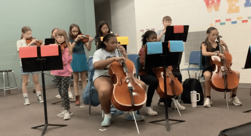 Picture of Tharp students plucking their instruments.