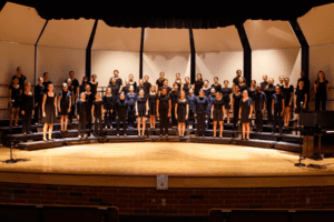 singers standing together in black outfits on a stage